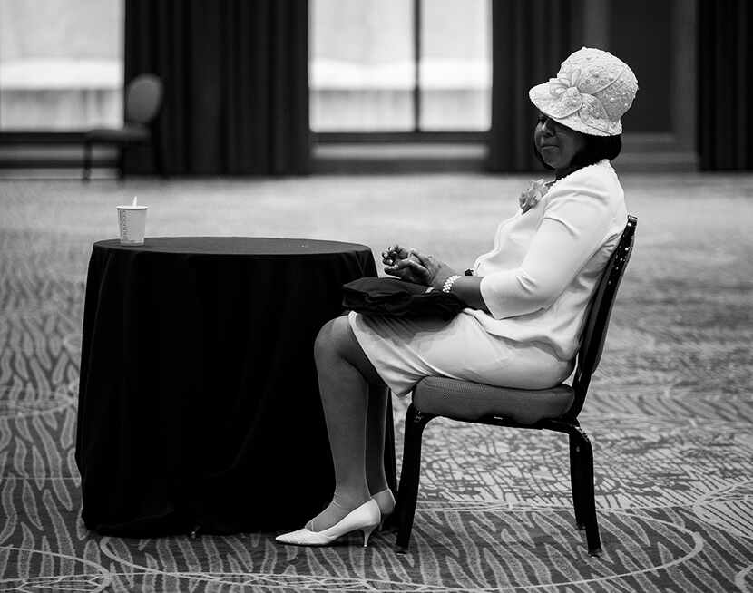  A woman wearing a white hat waits in the hallway before a communion and feet washing...