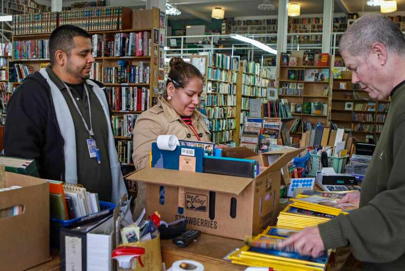 
Lucky Dog Books employee Mark Griffin rings up books and National Geographic magazines for...