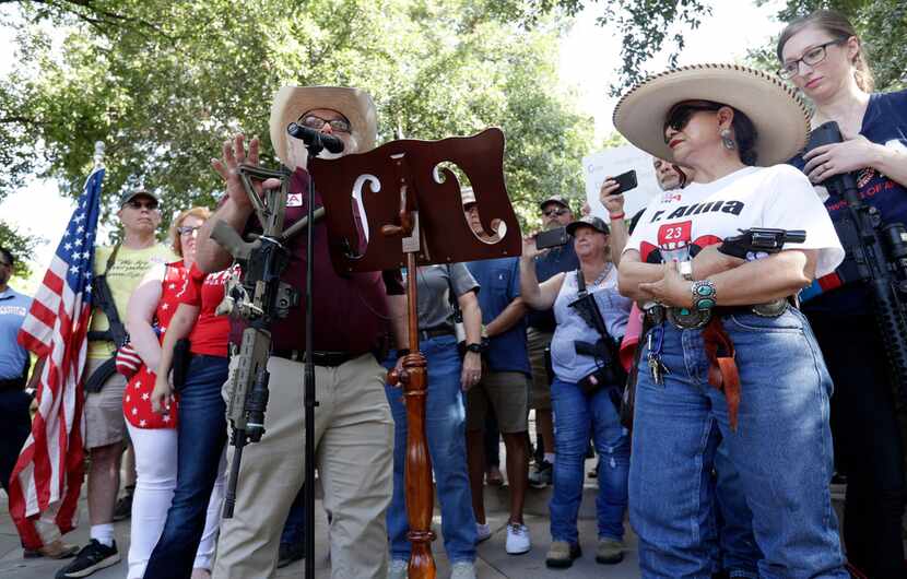 Steven Willeford holds up a rifle and Dr. Alma Arredondo-Lynch (right) holds a pistol as gun...