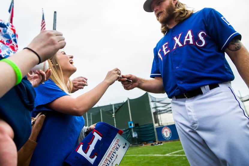 Texas Rangers starting pitcher A.J. Griffin (64) signs autographs for fans during a spring...