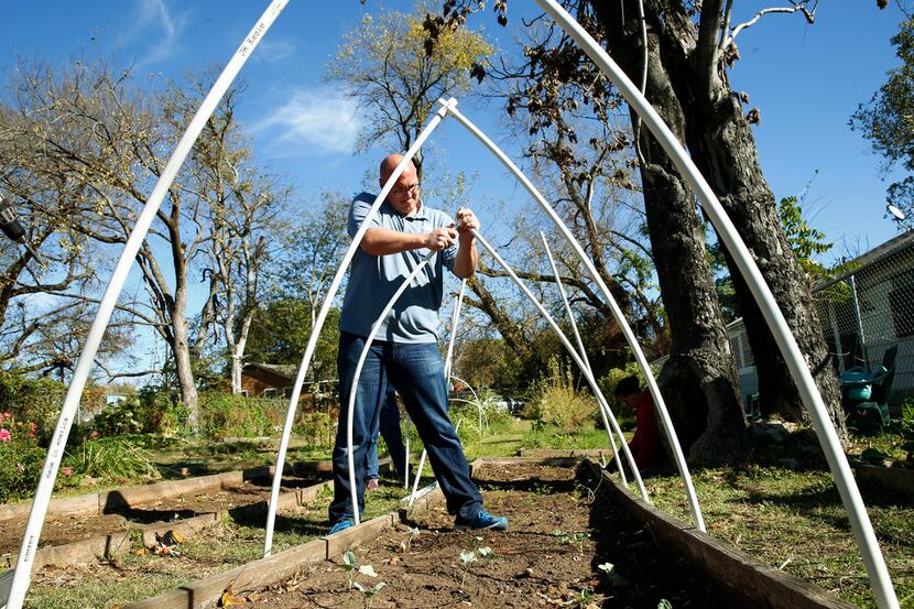 Daniel Cunningham puts up a garden cover using PVC pipe at Sunny South Community Garden in...