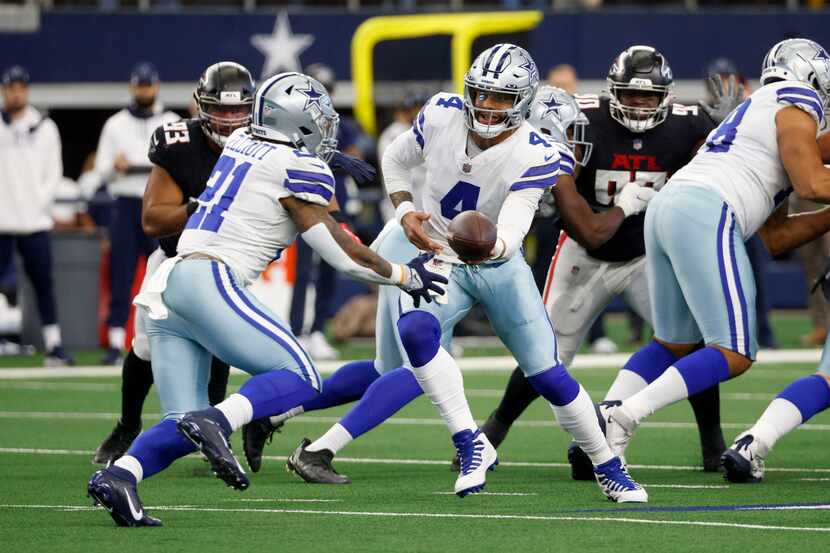 Dallas Cowboys quarterback Dak Prescott (4) hands the ball to running back Ezekiel Elliott...