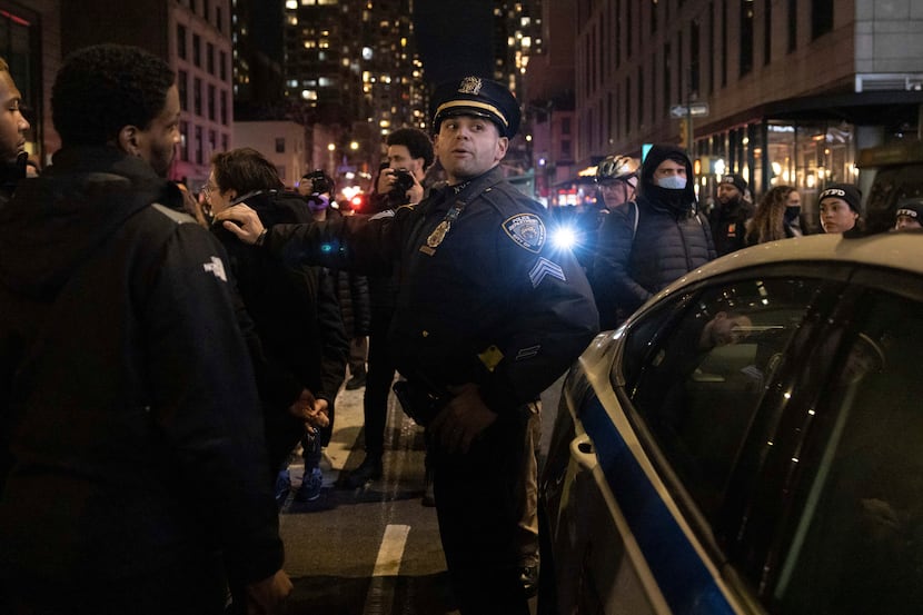 A police officer stands amongst demonstrators marching during a protest Saturday, Jan. 28,...