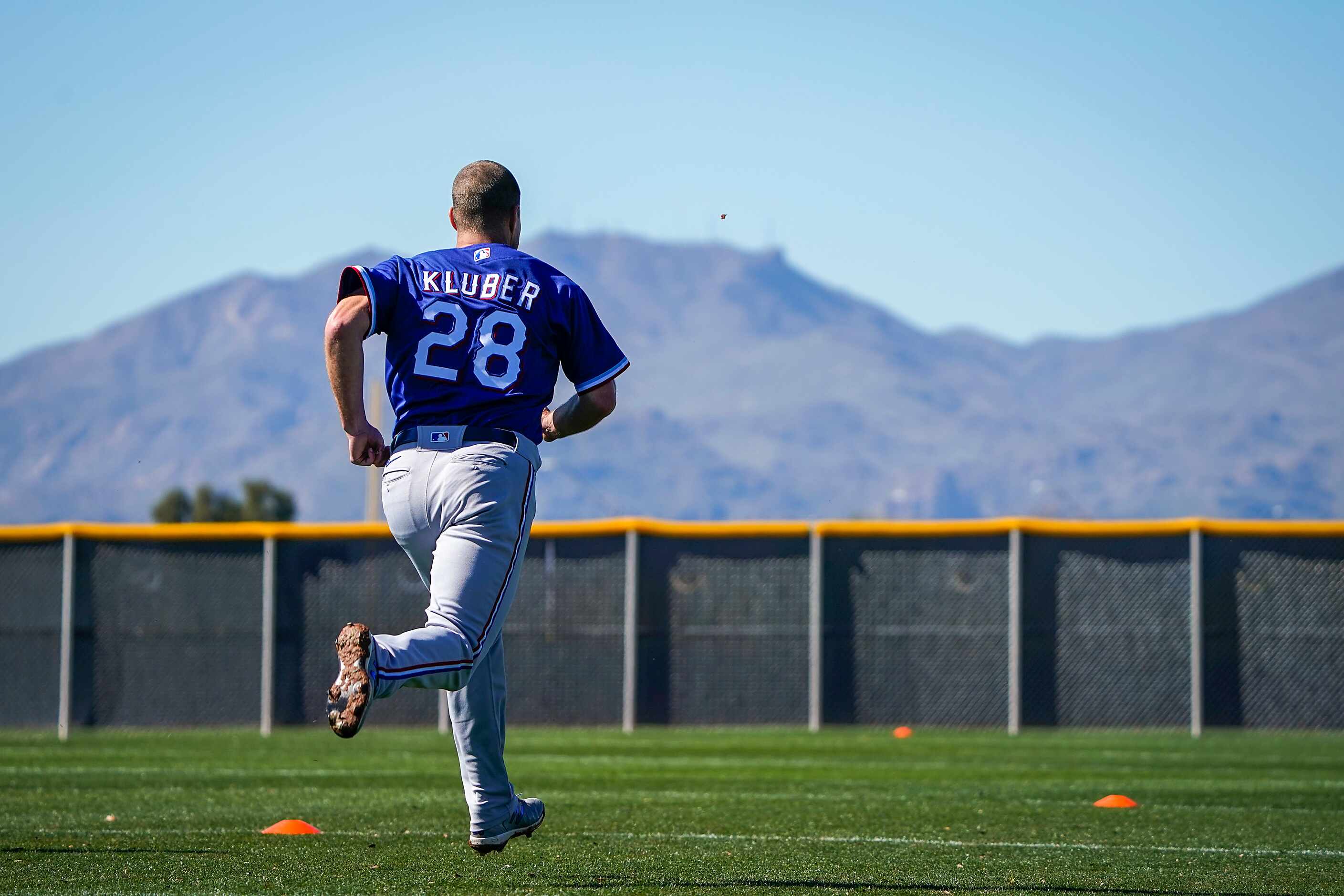 Texas Rangers pitcher Corey Kluber runs on a conditioning field during a spring training...