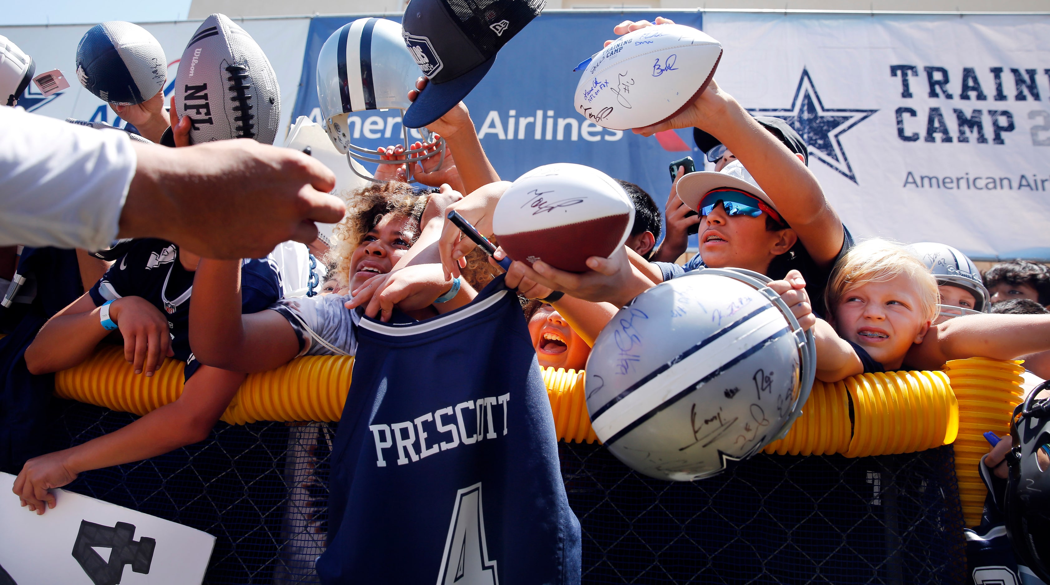 Young fans squeeze through the crowd in hopes of getting an autograph from Dallas Cowboys...