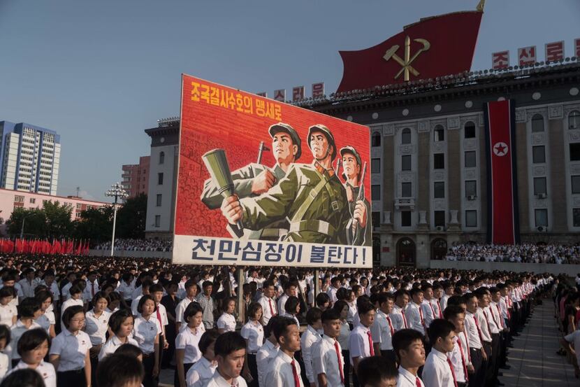 People wave banners and shout slogans as they attend a rally in support of North Korea's...