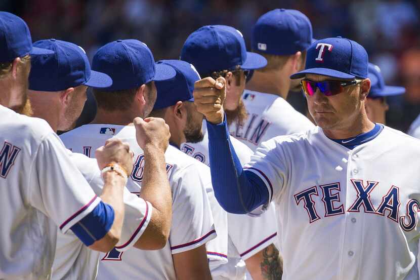 Texas Rangers manager Jeff Banister high fives his players during introductions before a...