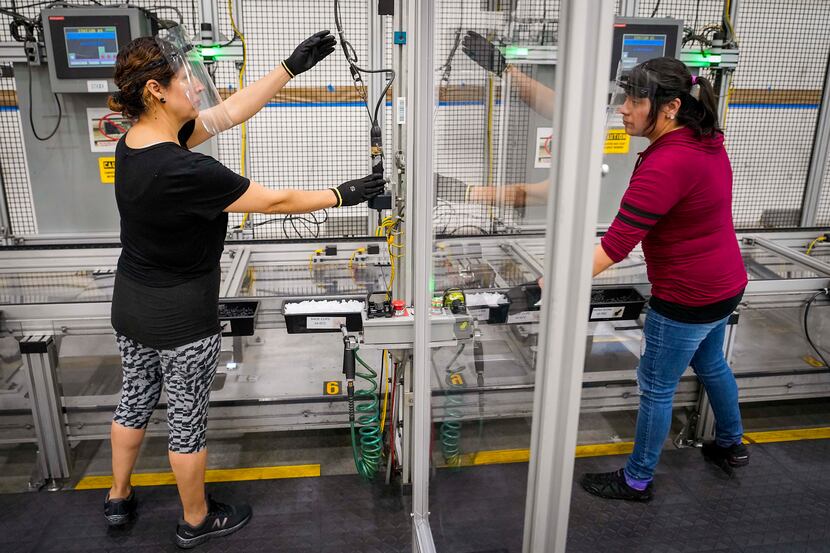 Blanca Ortega, left, and Sacnite Sanchez are separated by a clear barrier on a production...