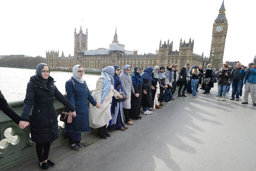 A group of women, some with their daughters, link hands on Westminster bridge in central...