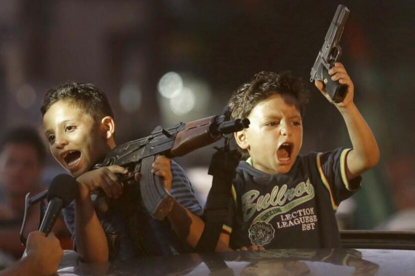 
Children, too, displayed weapons as Palestinians gathered in the streets to celebrate after...