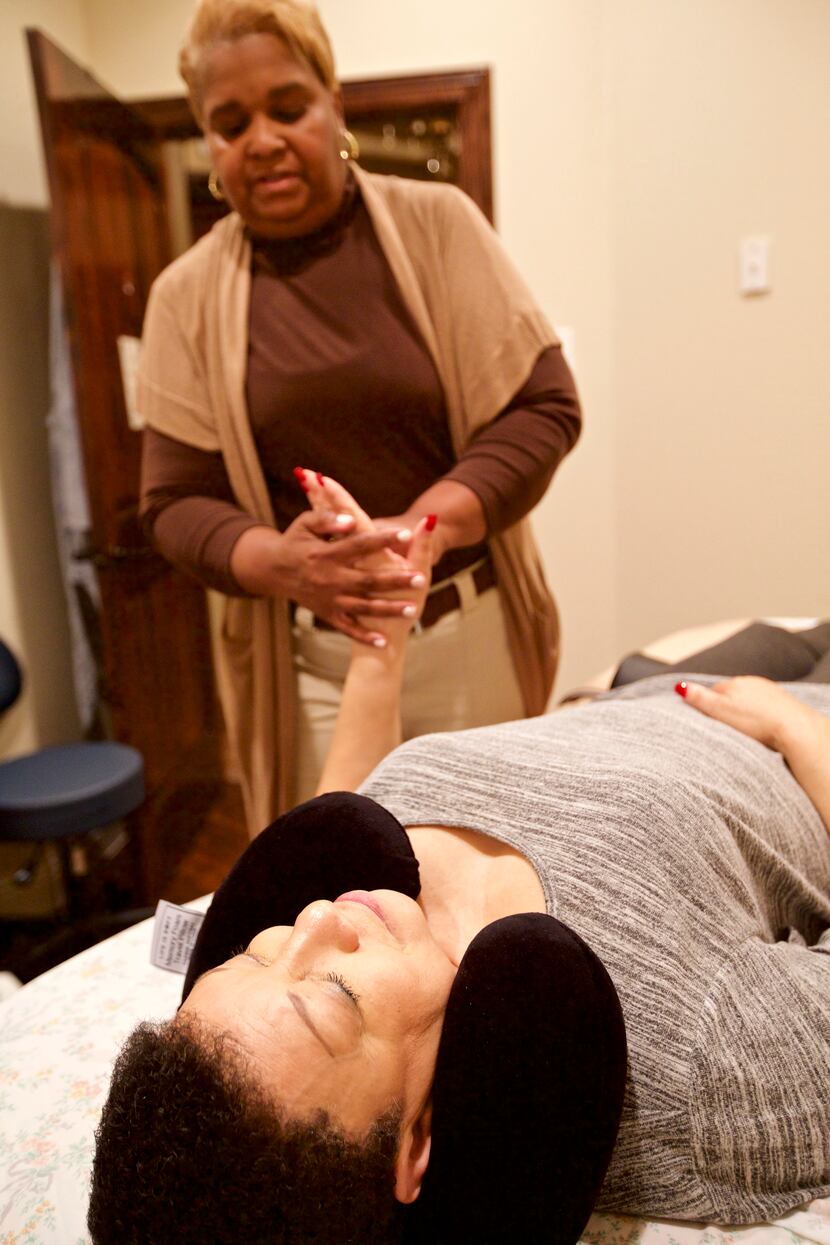 Licensed massage therapist Thalia Jackson Abdelrahim massages Marsha Conley's hand during a...
