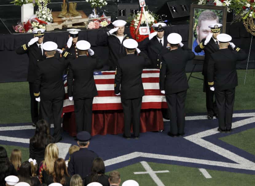 Military members salute during a memorial service for Chris Kyle at Cowboys Stadium in...