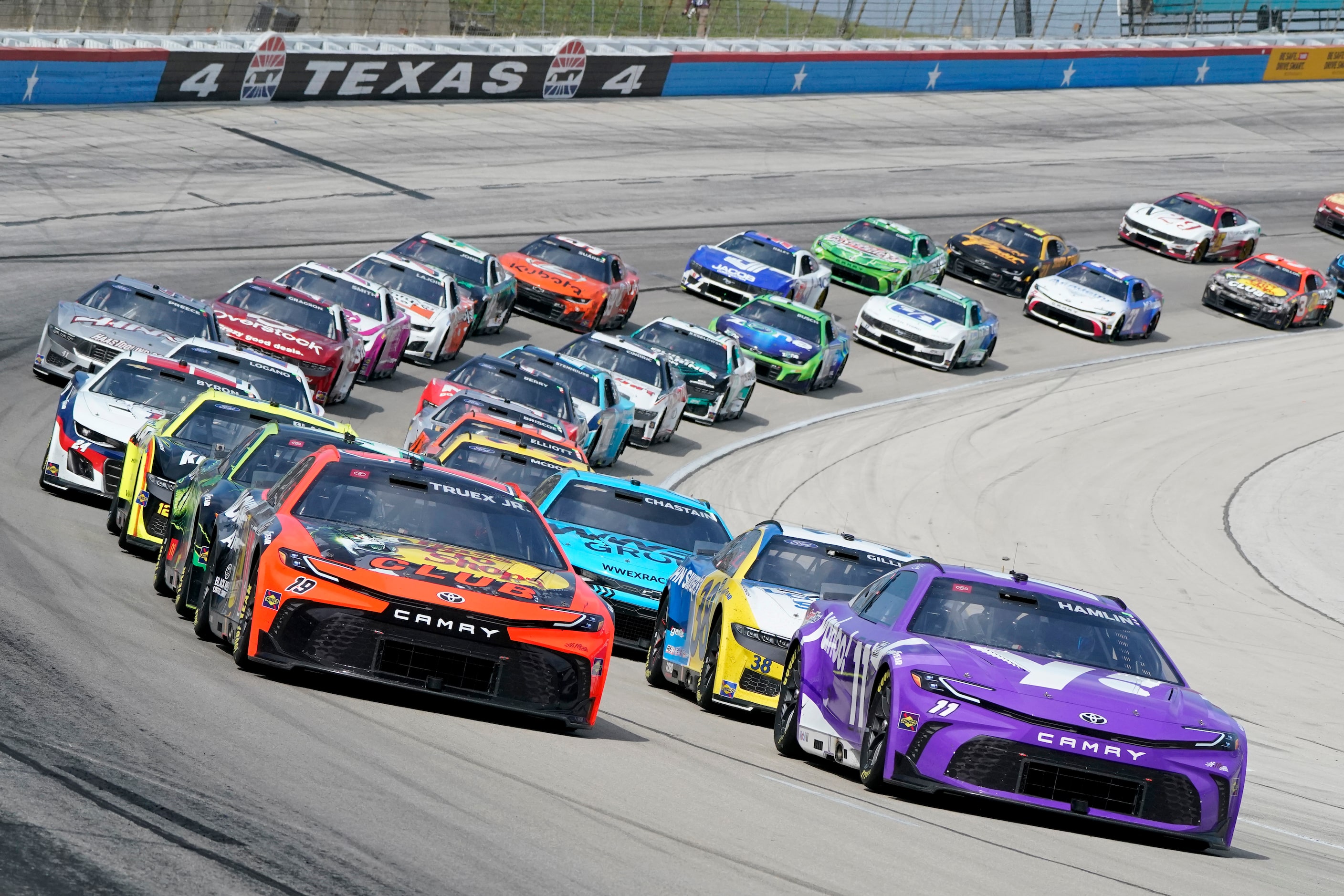 Martin Truex Jr (19) and Denny Hamlin (11) come out of Turn 4 during a restart in a NASCAR...