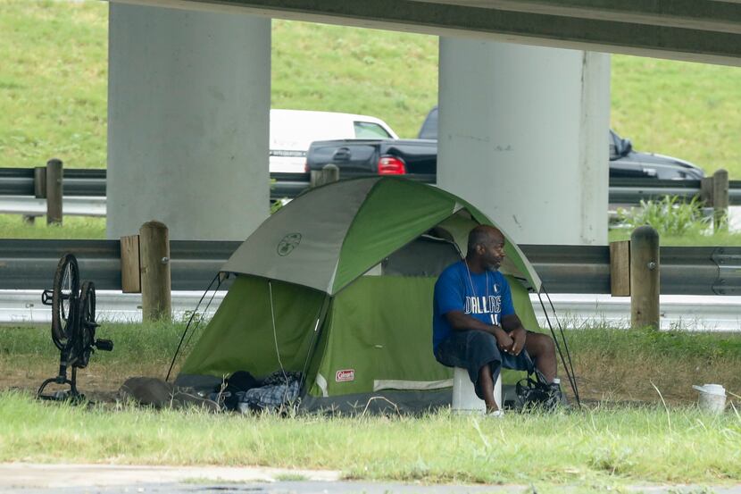 A man sits outside his tent underneath I-35 near downtown on Wednesday, Aug. 18, 2021, in...