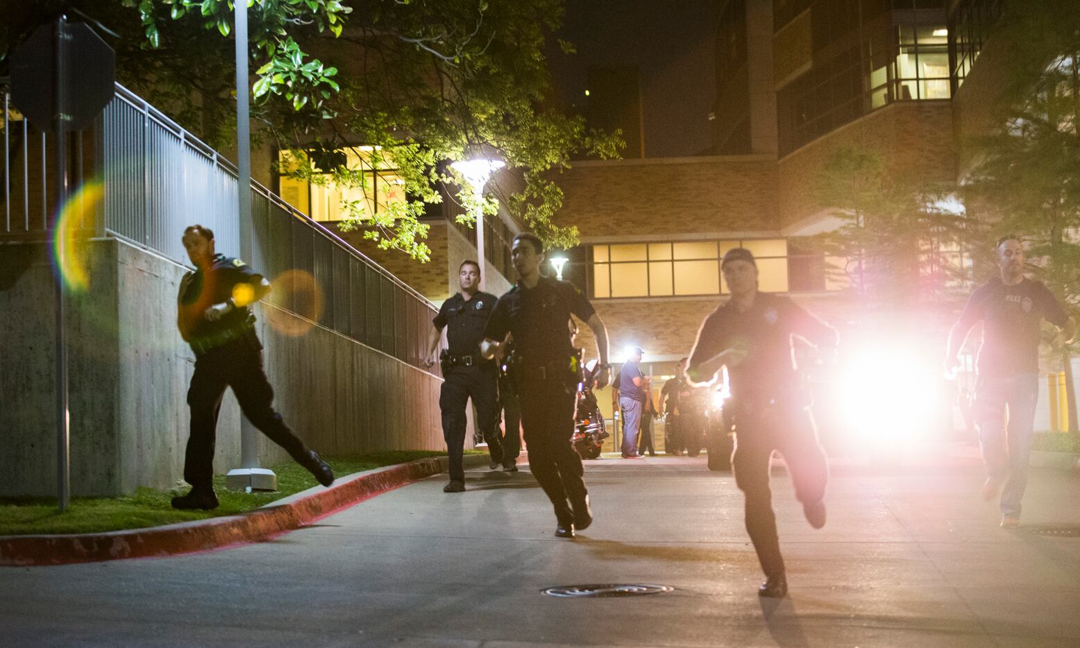 Police officers run away from the emergency room to their cars at Texas Health Presbyterian...