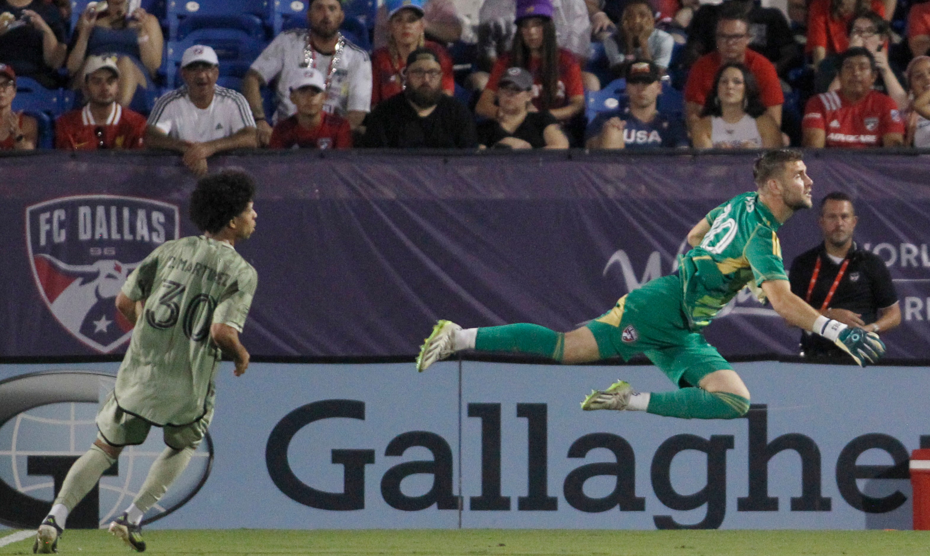 FC Dallas goalkeeper Maarten Paes (30), right, springs from the net to re-route the ball...