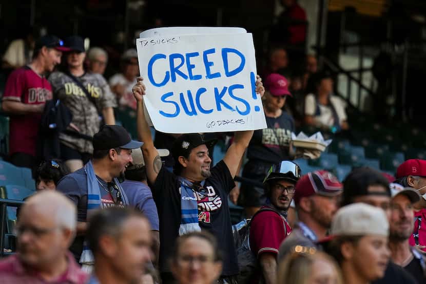 A fan of the Arizona Diamondbacks holds a sign disparaging the rock band Creed prior to in...