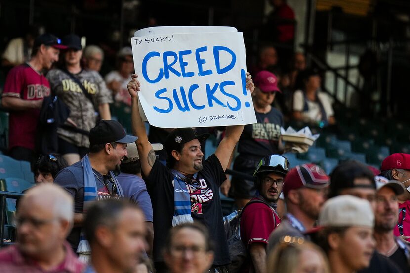 A fan of the Arizona Diamondbacks holds a sign disparaging the rock band Creed prior to in...