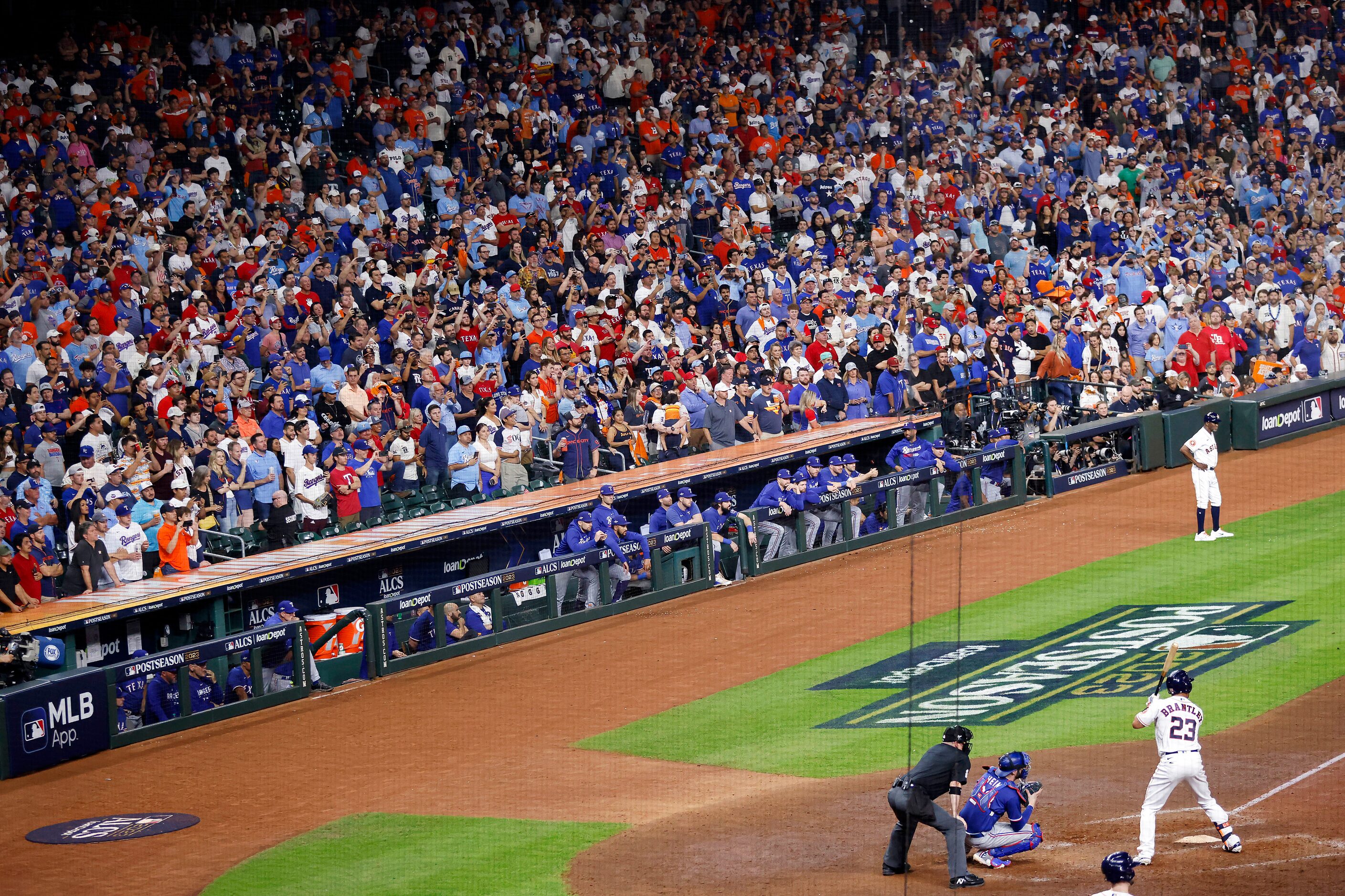 Texas Rangers fans fill the lower seating section behind the team dugout in the ninth inning...