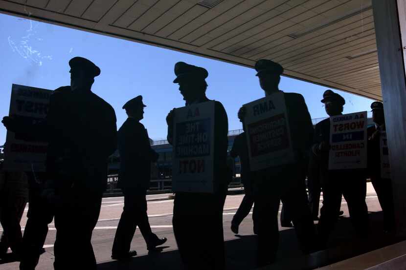 American Airlines pilots on a picket line are reflected in the plate glass window of the...