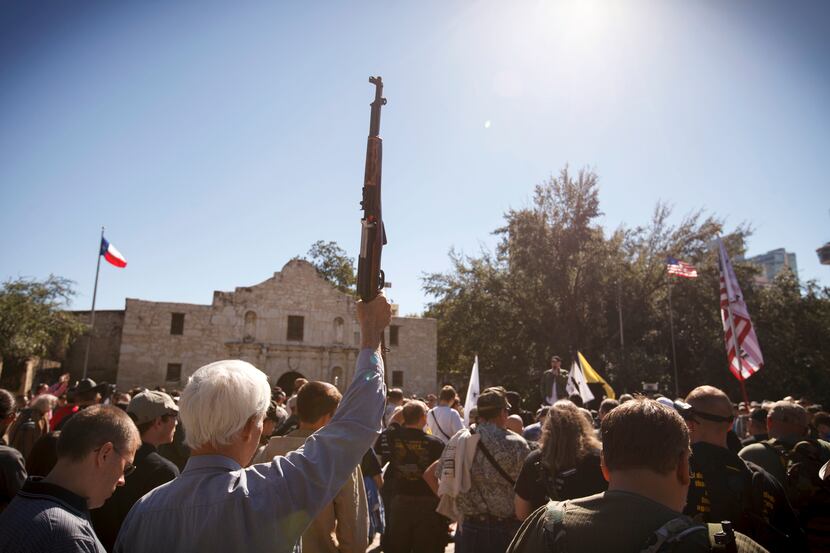 A demonstrator raises his rifle during a pro-gun rally at the Alamo in San Antonio, Oct. 19,...