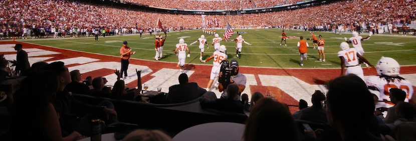 A Texas Longhorns fan, lower left, gives the "hook 'em horns" sign as guests are merged with...