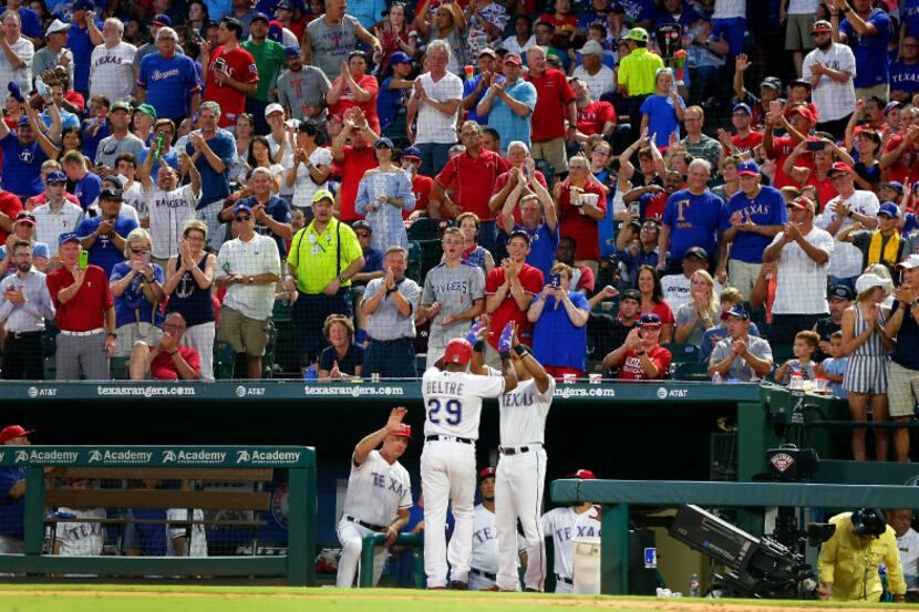 With a standing ovation, Texas Rangers Adrian Beltre (29) is welcomed to the dugout by...