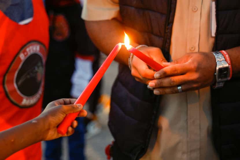 Preston Malone II (right) lights a candle before a balloon release in memory of 11-year-old...