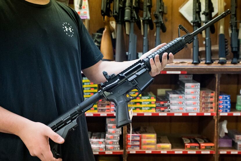 An employee holds an AR-15 style rifle inside Clark Brothers Gun Shop in Warrenton, Va....