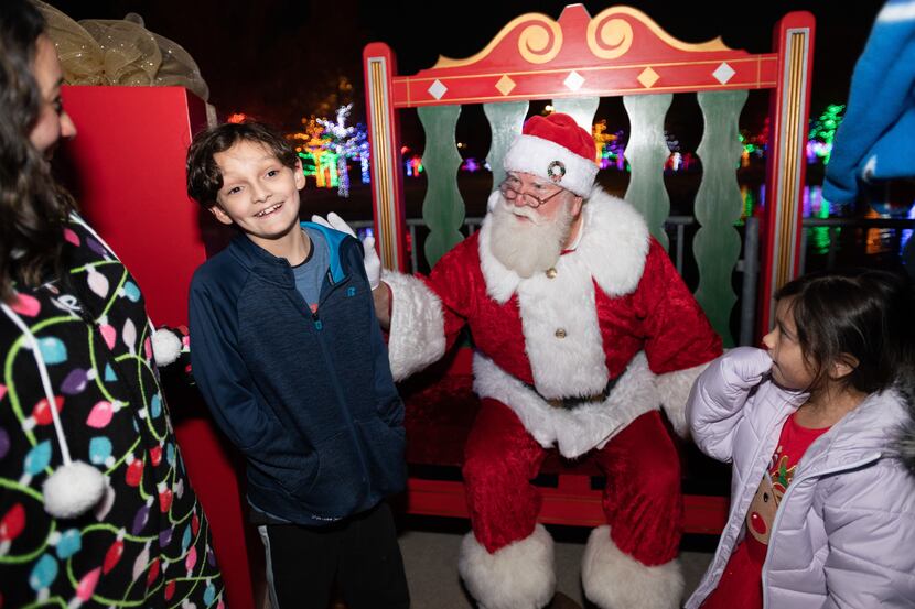 Jaxon Lopez, 8, left, reacts as Santa Claus asks him and his sister Sara Lopez what they...