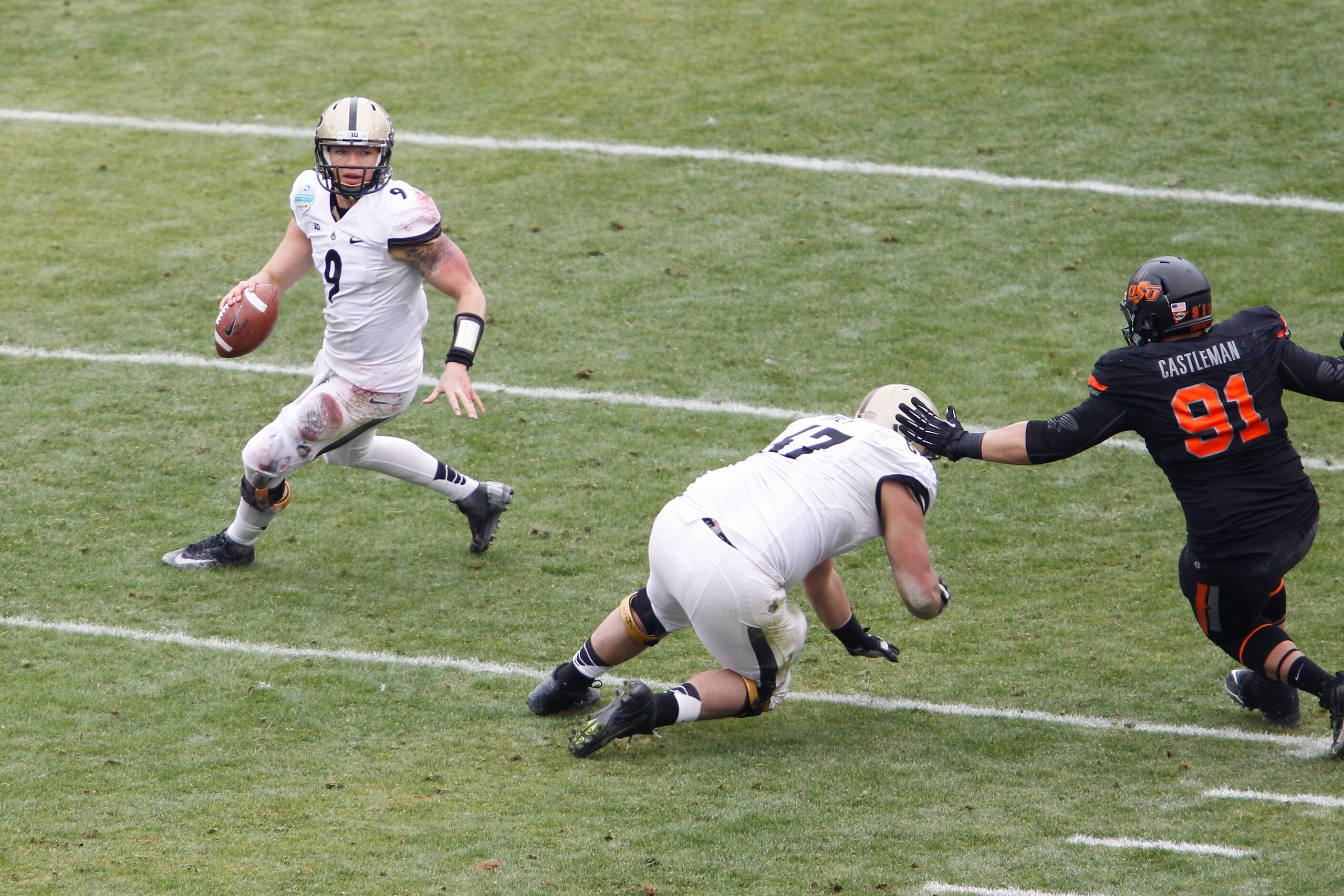 Purdue's Robert Marve (9) scrambles as Oklahoma State defense pressures him out of the...