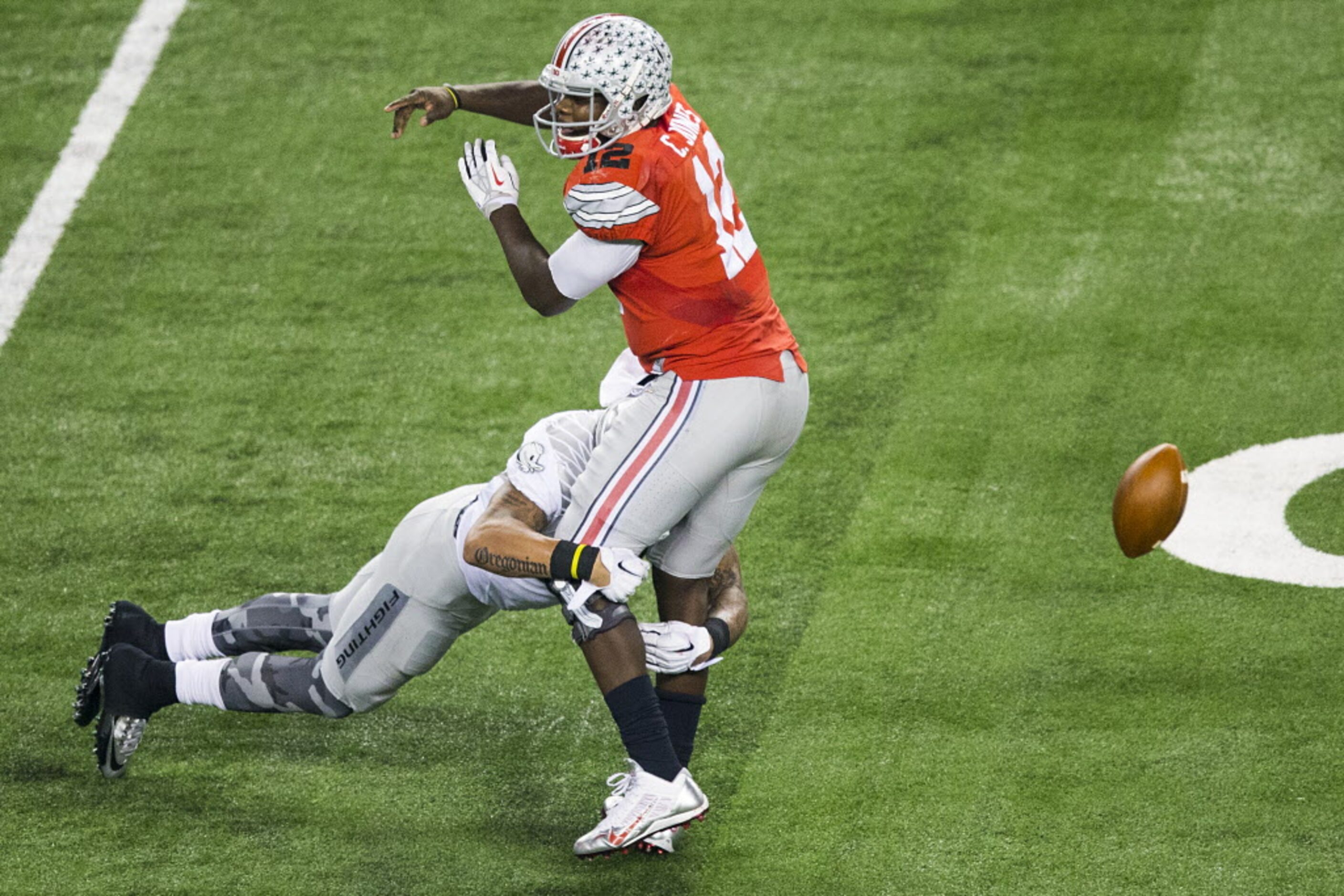 Ohio State Buckeyes quarterback Cardale Jones (12) fumbles as he is hit by Oregon Ducks...