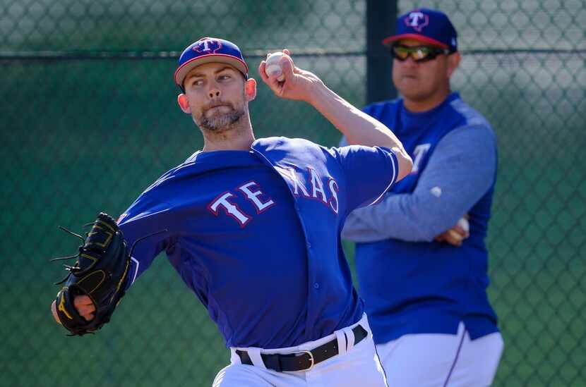 Texas Rangers pitcher Mike Minor throws a bullpen session as pitching coach Julio Rangel...