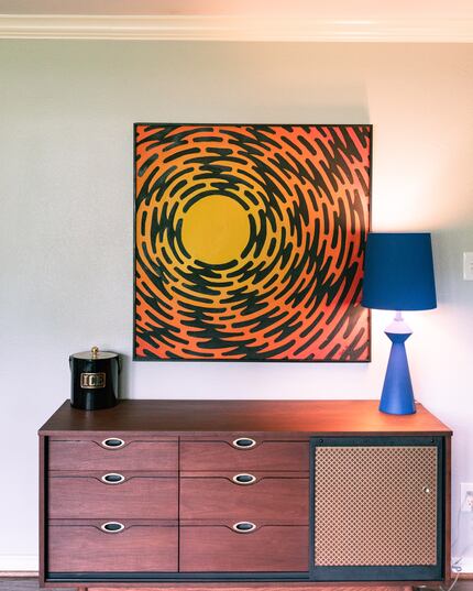 Wooden console table with a blue lamp and abstract art behind.