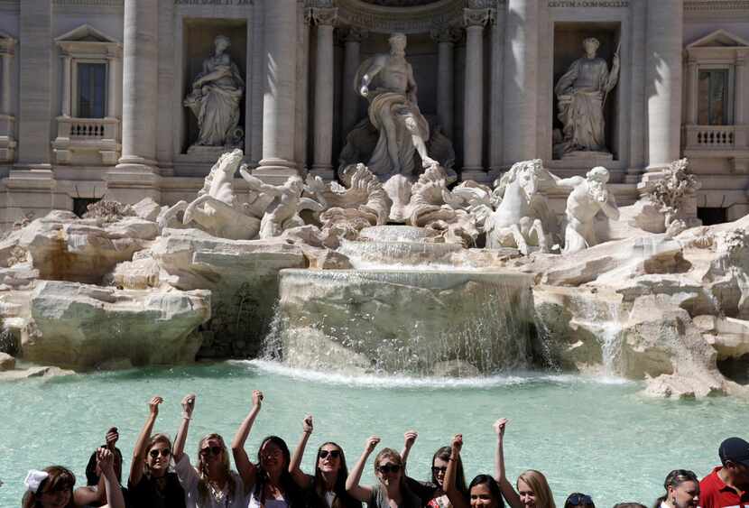Tourists throw their coins in the Trevi Fountain in Rome. The fountain is featured in...