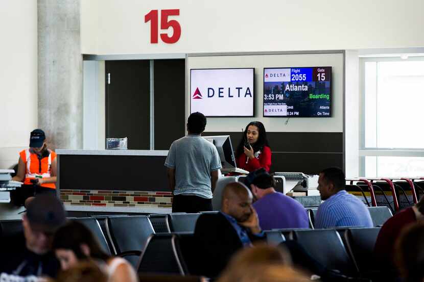 A Delta Air Lines agent  announces boarding for an Atlanta-bound flight from Love Field Gate...