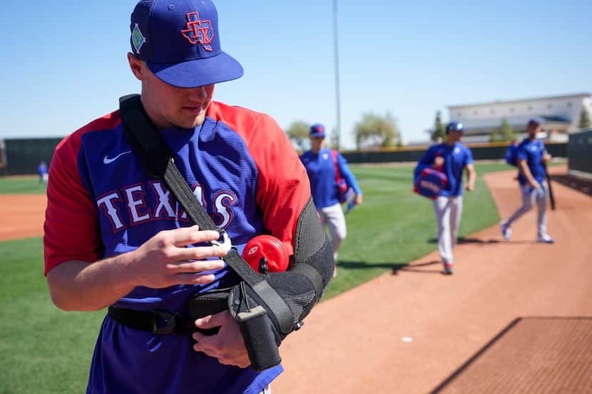 Texas Rangers infielder Josh Jung wears a sling  during a spring training workout at the...