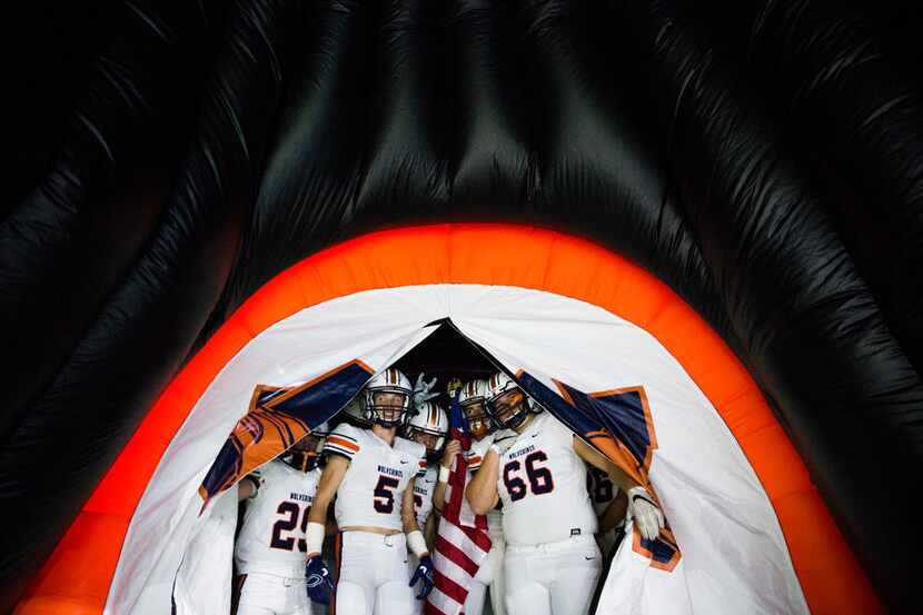 Frisco Wakeland football players peak through an inflatable helmet before a Class 5A high...