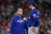 Texas Rangers head athletic trainer Matt Lucero checks on starting pitcher Dane Dunning...