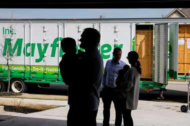 The Rosvold family is silhouetted against the freight truck while the movers unload their...