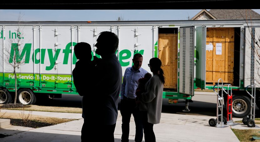 The Rosvold family is silhouetted against the freight truck while the movers unload their...