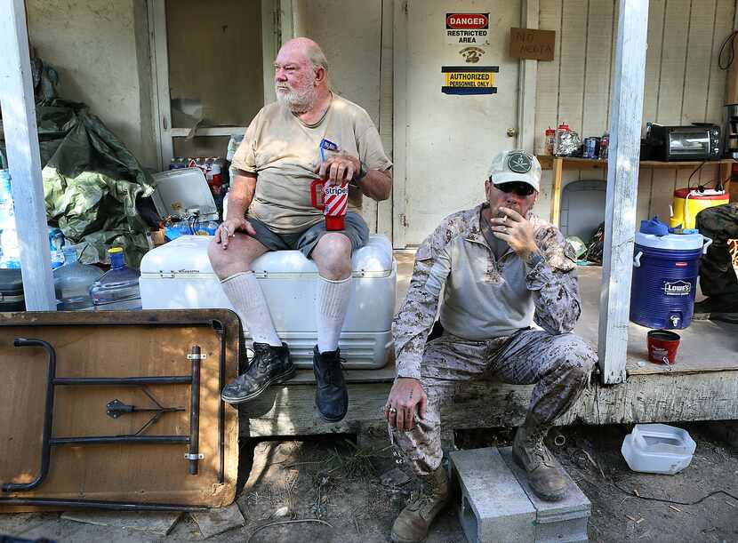 Kevin Massey, right, takes a drag on a cigarette as he sits with land owner Rusty Monsees...