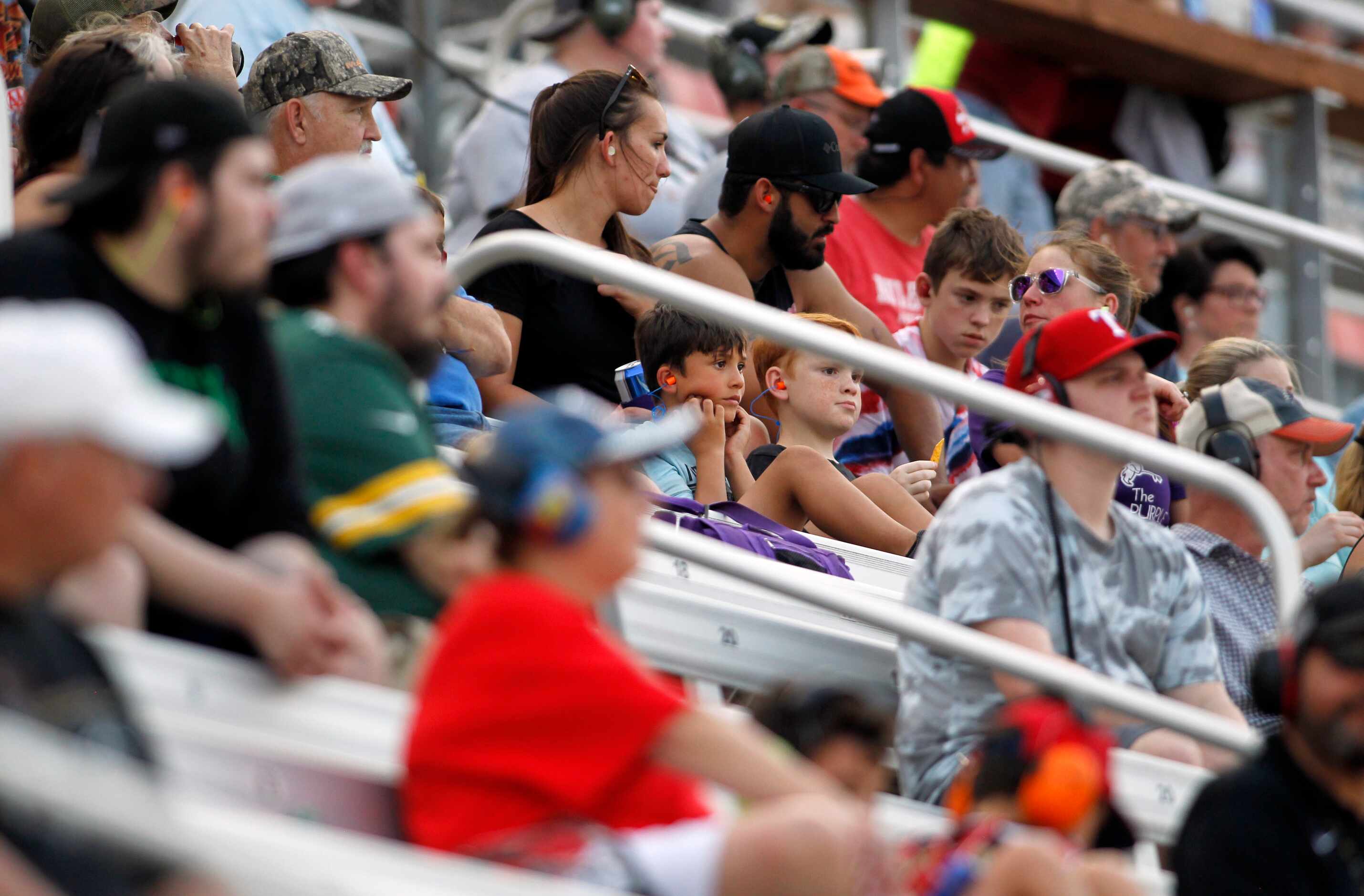A pair of young race enthusiasts take in race action as they are framed by older fans during...