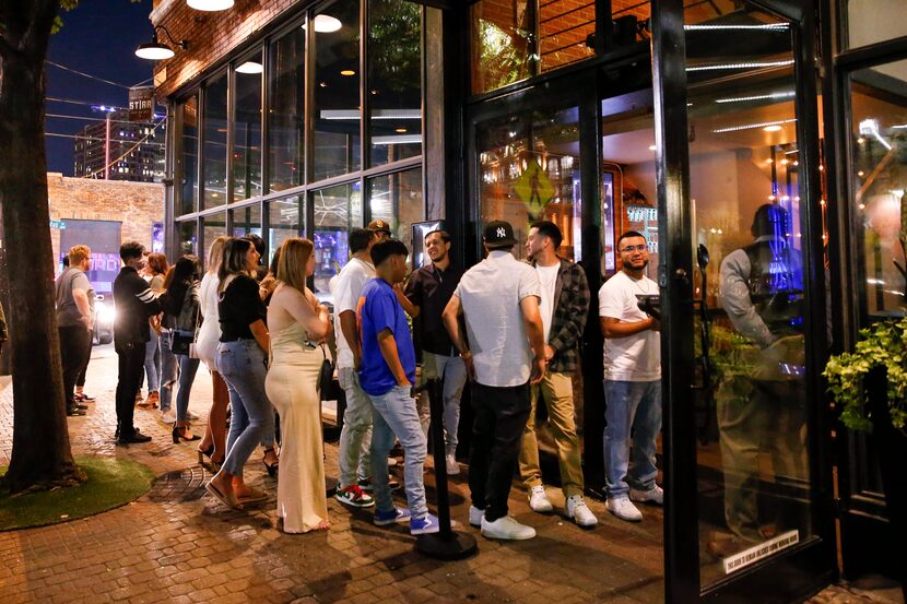 People wait outside to enter Stirr, a bar and restaurant on Main Street in in Deep Ellum.