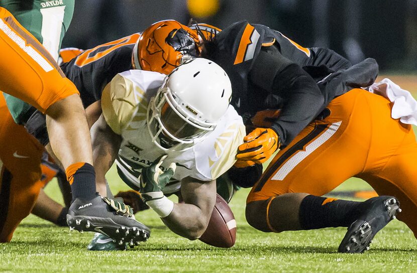 Baylor running back Shock Linwood (32) loses a fumble as he is brought down by the Oklahoma...