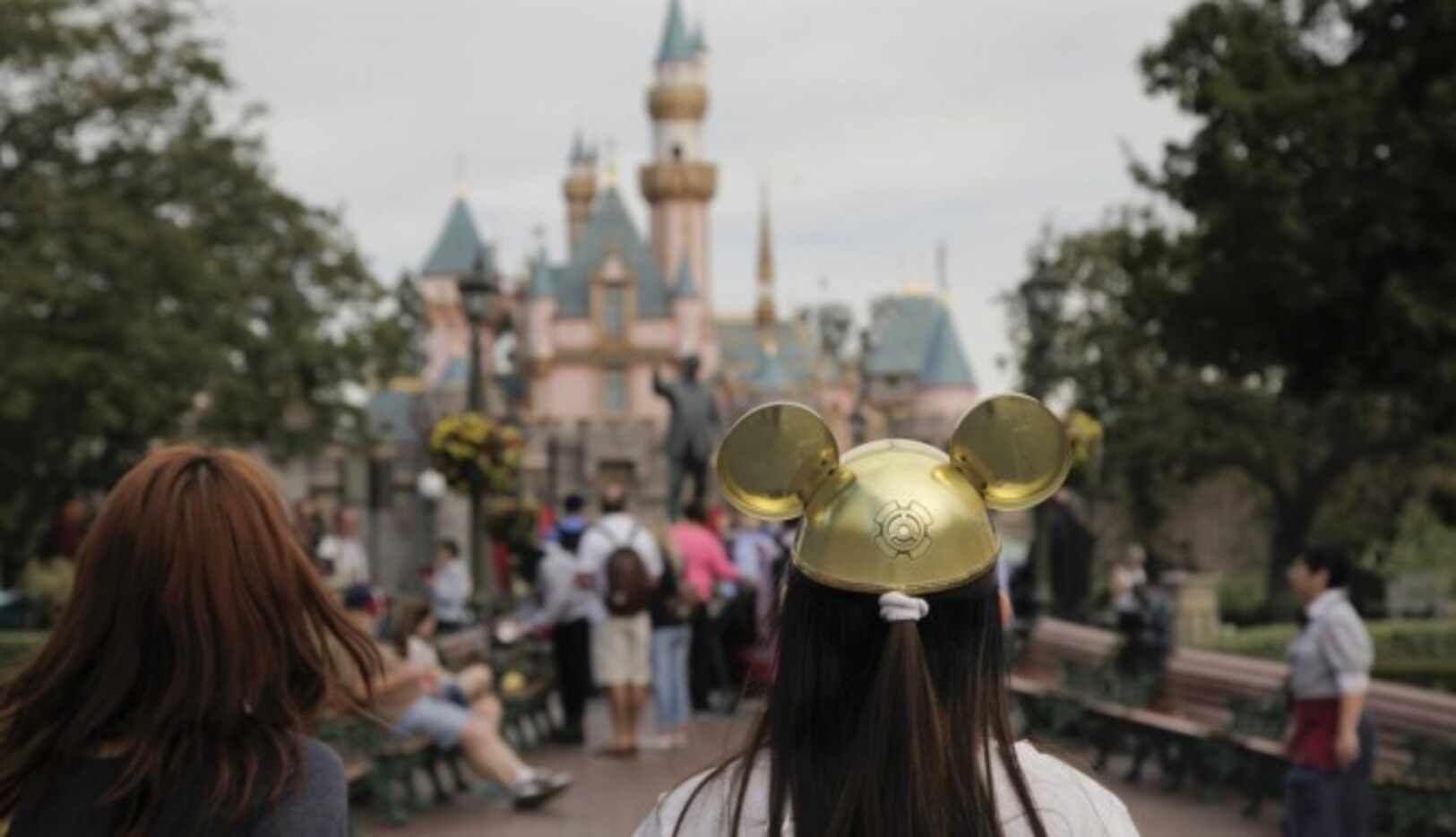 Una mujer con un sombrero de Mickey Mouse camina por Disneyland, donde se originó un brote...