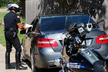 Garland police Officer Lanny Orman writes a citation for texting while driving through a...
