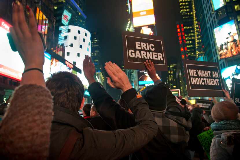 Protesters in Times Square raise their hands and chant while carrying signs in reaction to a...