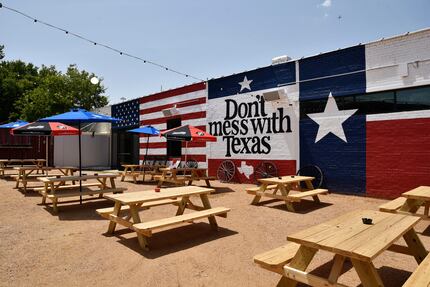 Opposite this fenced-in outdoor area at Mama Tried is a shipping container that serves as a...