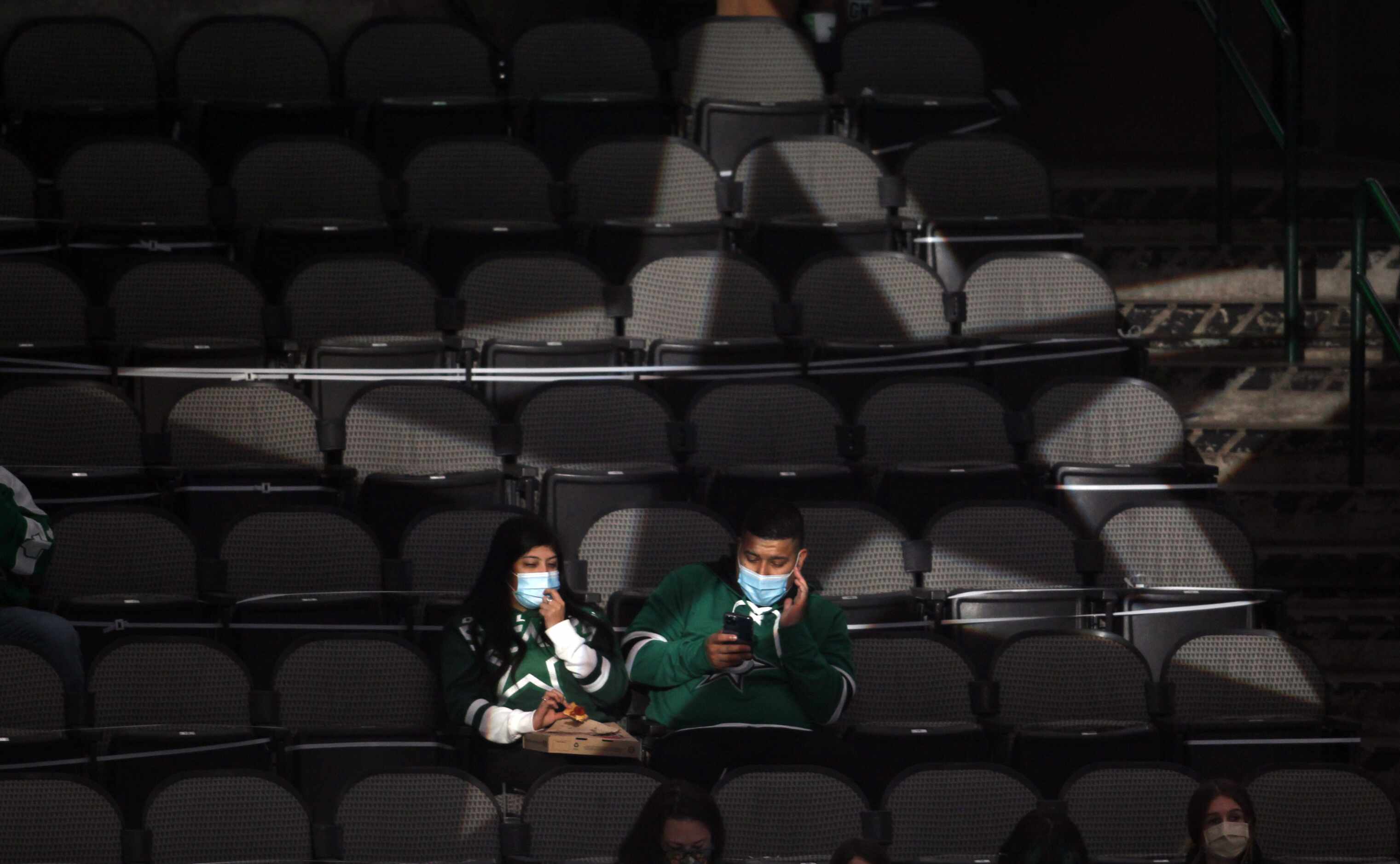 A couple of Dallas Stars fans are illuminated and framed by an illuminated star passing...